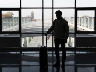 Bărbat cu troler într-un terminal de aeroport, pregătit să își continue călătoria după aterizare